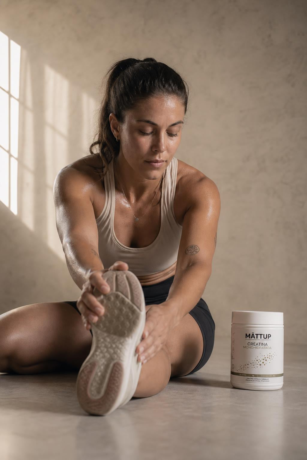 Mujer estirando después de entrenar con el bote de Creatina MĀTTUP junto a ella